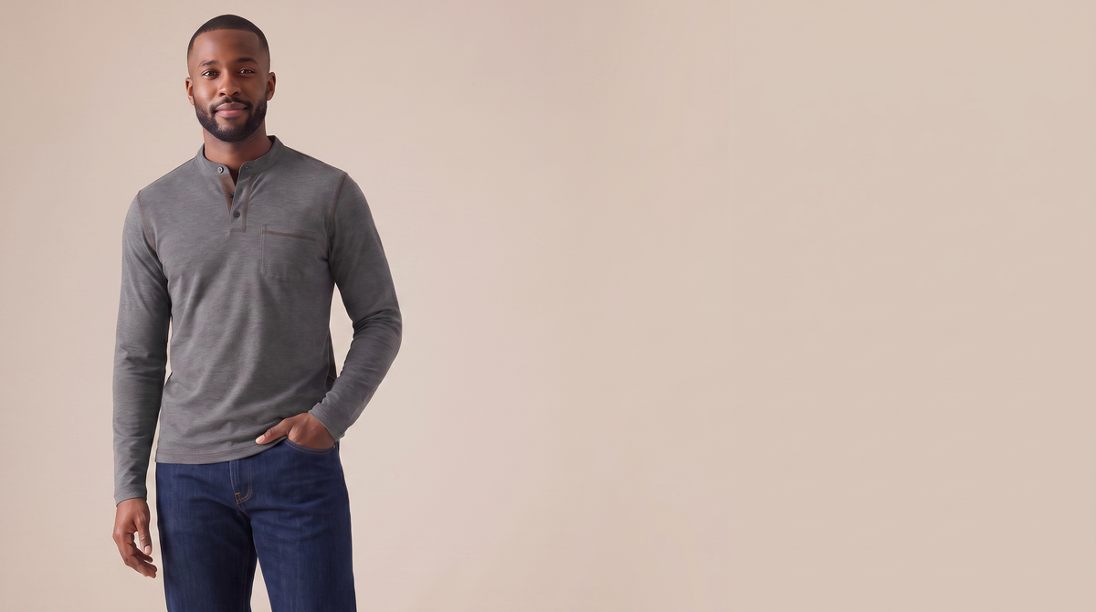 Man in a charcoal henley on a plain stone backdrop